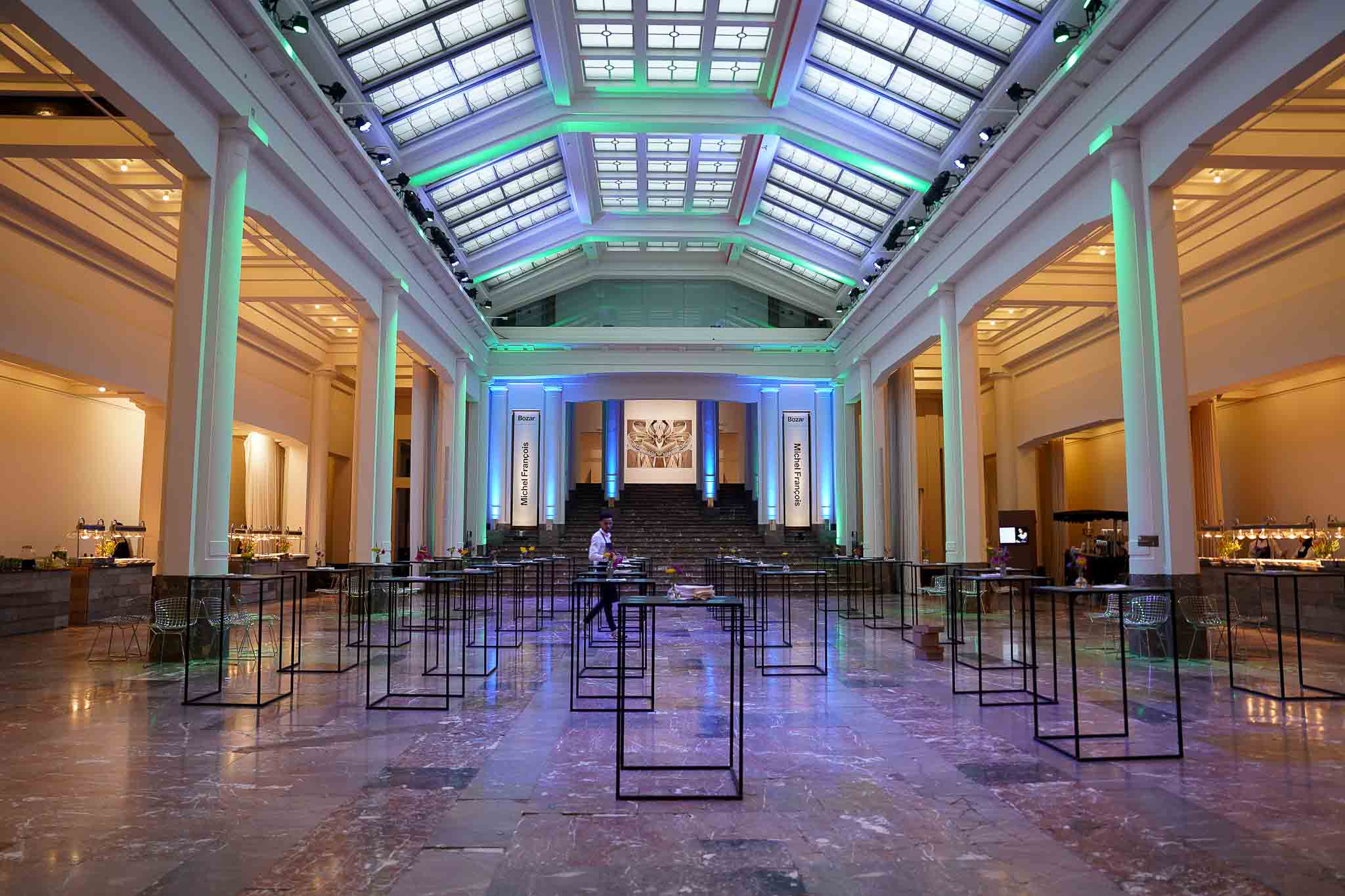 Grote witte zaal met tafeltjes en ramen op het plafond.