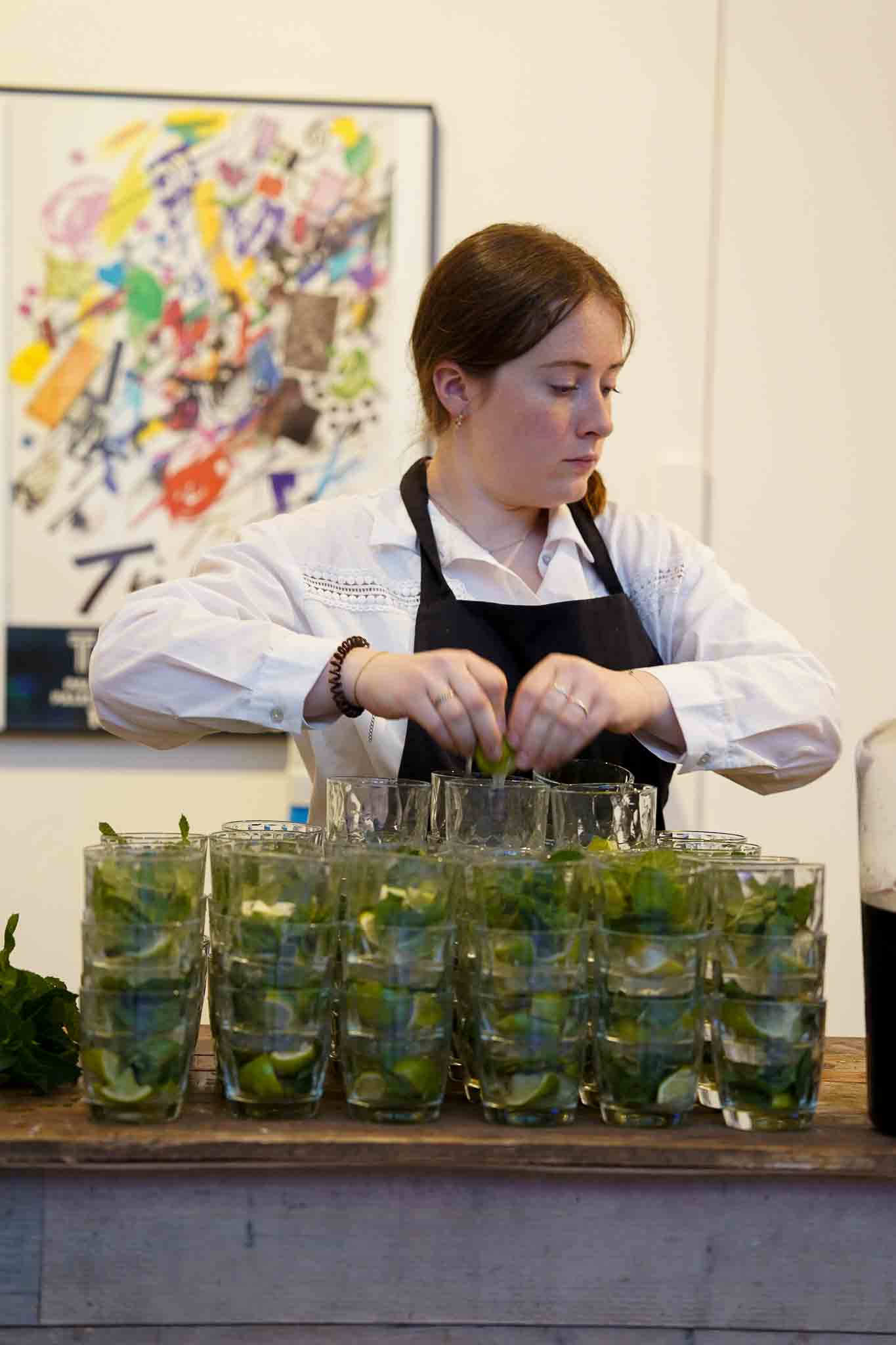 Werkneemster maakt verschillende mojito limoen cocktails klaar.